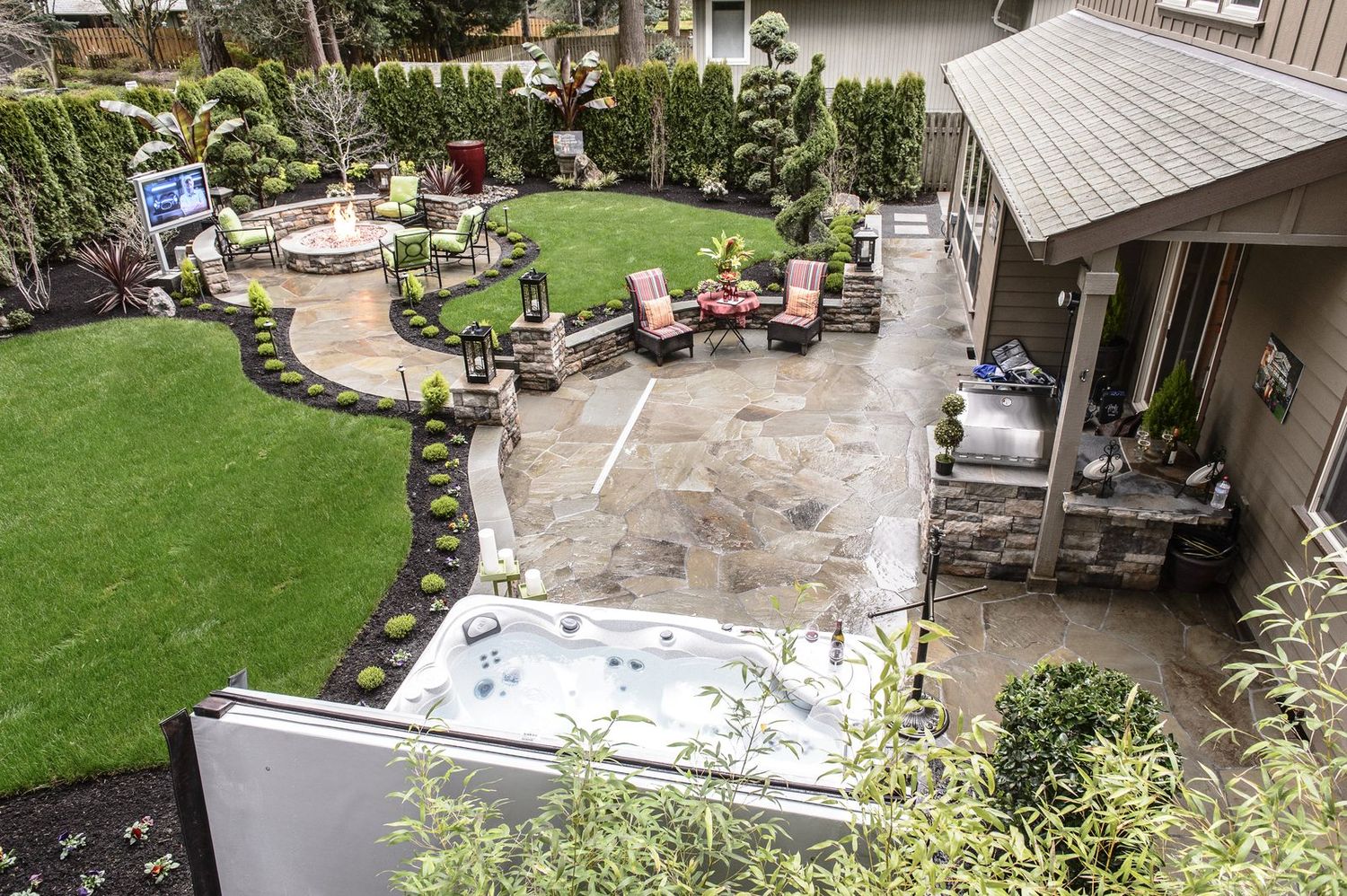 After — finished outdoor living space with fire pit, flagstone patio, and spa