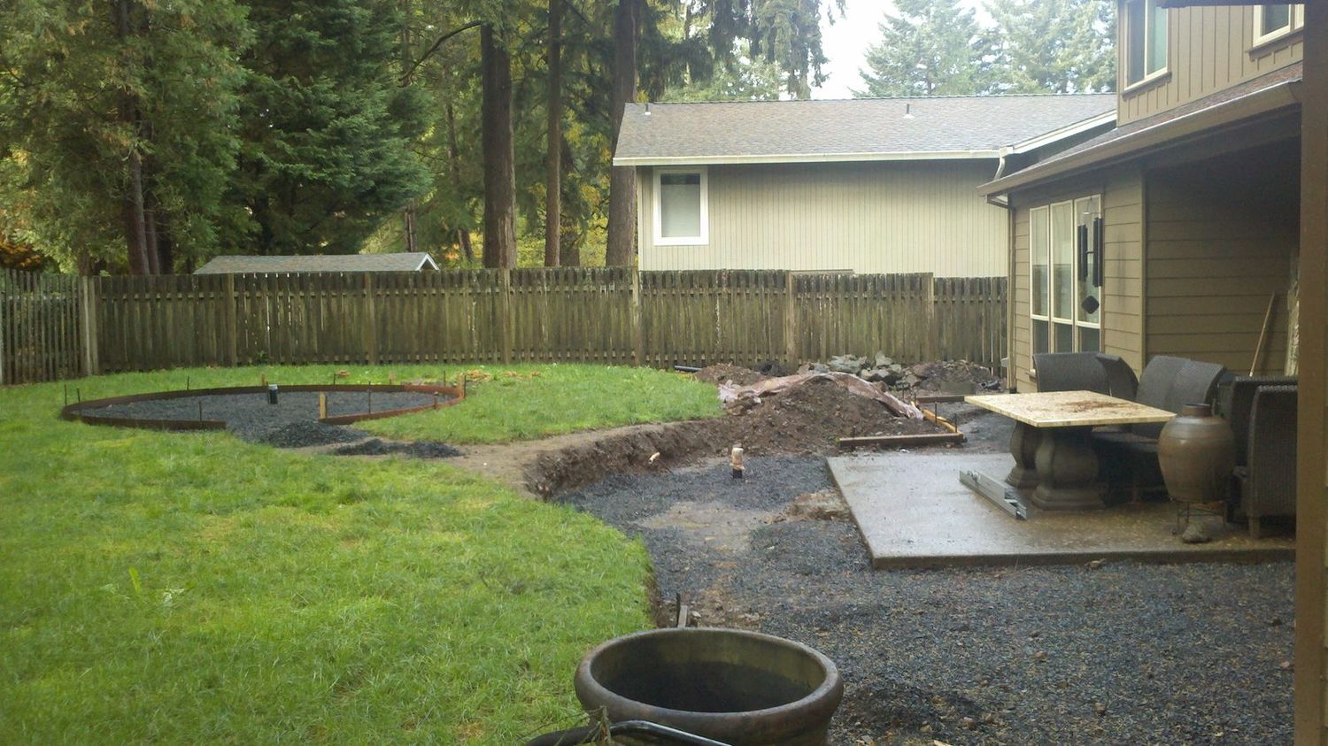 Before — bare dirt and gravel backyard during construction